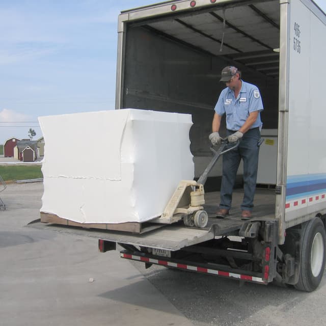 Packaged playhouse kit being lowered from semi truck trailer via lift gate.