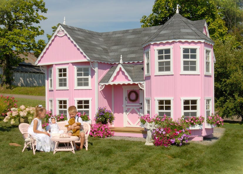 Sara's Victorian Mansion playhouse in pink with two children in front having a tea party.